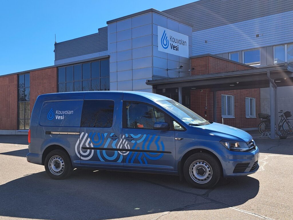 Kouvolan Veden sininen pakettiauto toimitilojen edessä.