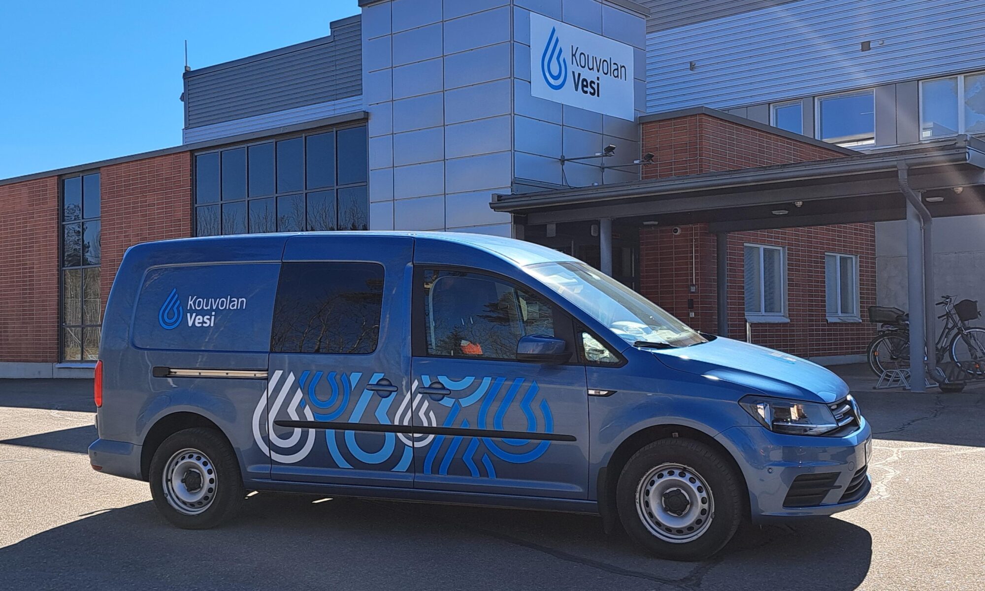 Kouvolan Veden sininen pakettiauto toimitilojen edessä.