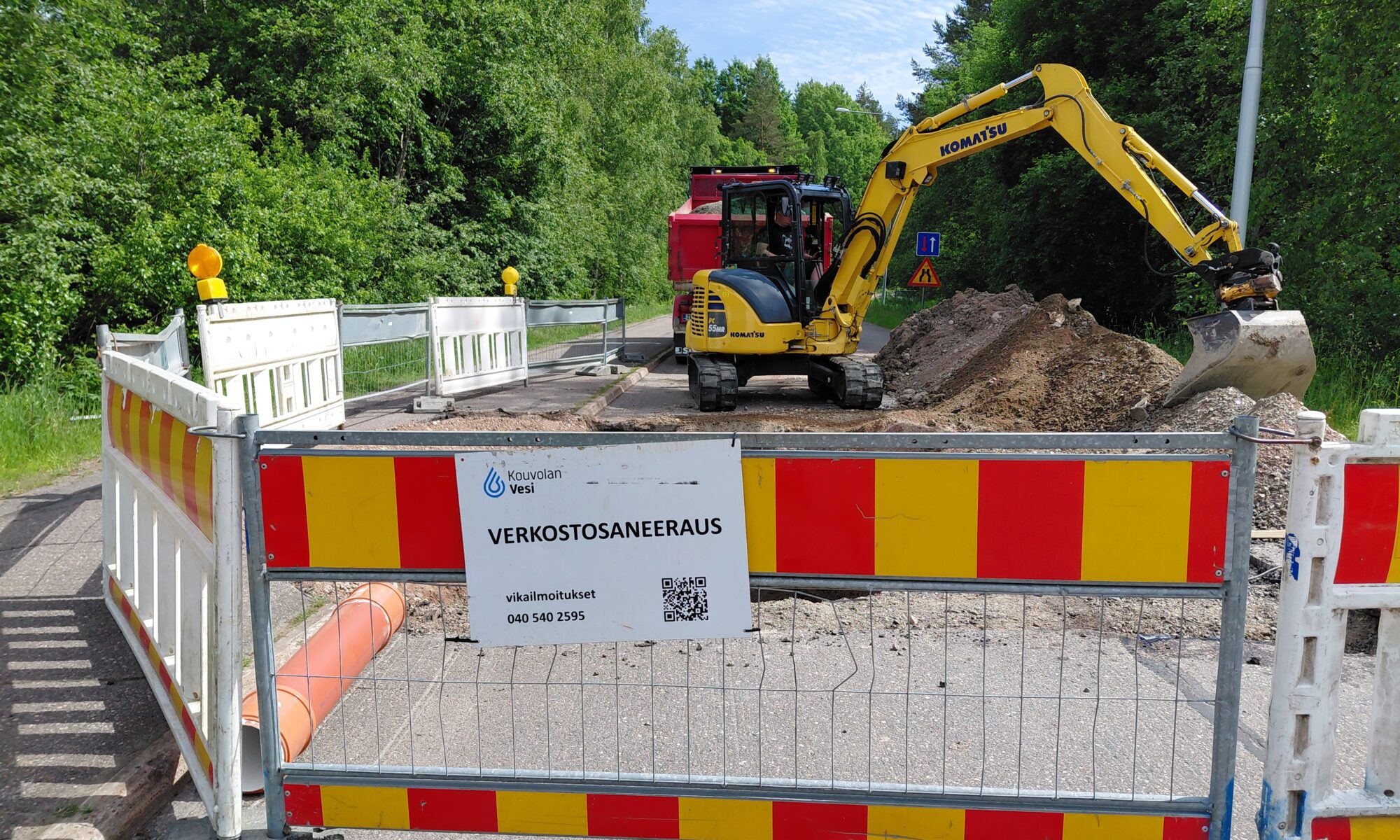 Kaivinkone kaivaa maata saneeraustyömaalla, ympärillä työmaa-aidat.
